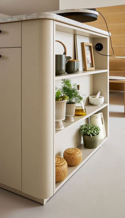 Moderne Kücheninsel mit offenen Regalen, gefüllt mit Pflanzen, Geschirr und dekorativen Körben. Helle, neutrale Farben dominieren das Design.